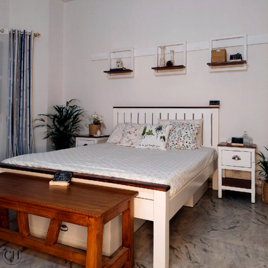 Bedroom with farmhouse-style bed and side table in white-and-wood finish, under-bed storage, wall frame shelves, wood footboard table