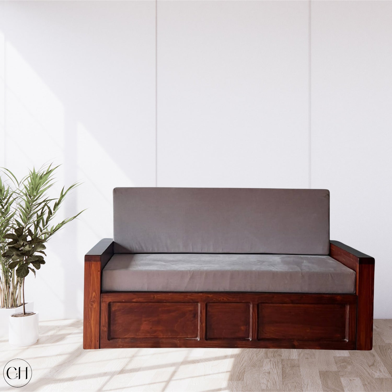 CustHum - Sofa-cum-bed in grey upholstery, placed against white wall with a couple of planters on the left
