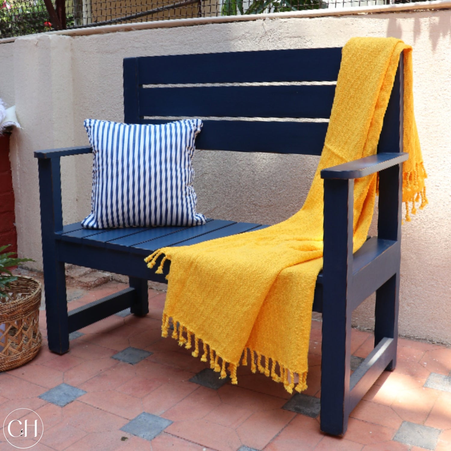 CustHum Blue outdoor bench, styled with yellow throw and blue striped cushion