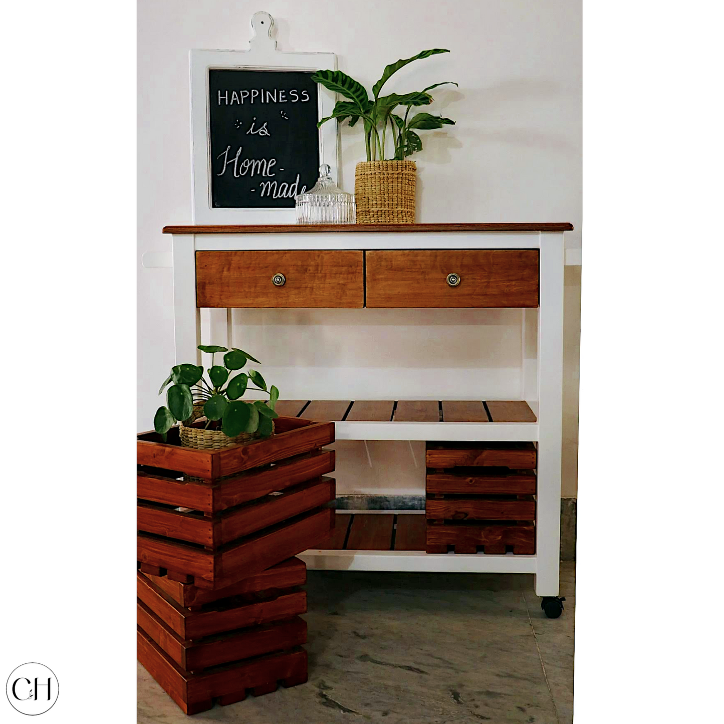 CustHum Belfast - Wooden kitchen island trolley, showing 2 crates stacked outside on the left and 1 crate on the bottom shelf, plant and decoratives on top